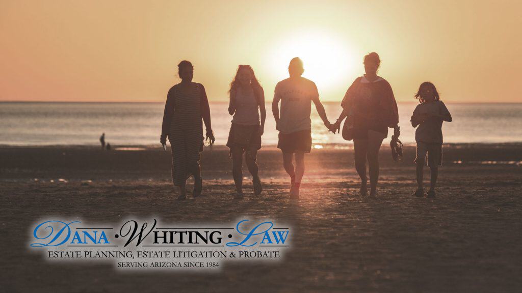 Family holding hands walking along the beach at sunset.