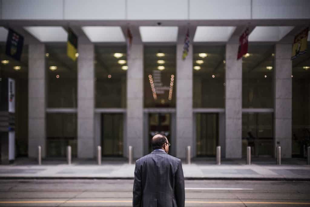 Man in business suit standing outside modern office building at night.