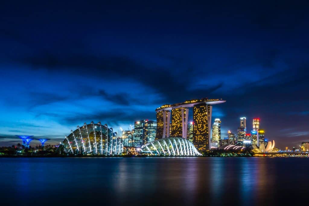 A nighttime view of Singapore's skyline featuring Marina Bay Sands and Gardens by the Bay illuminate.