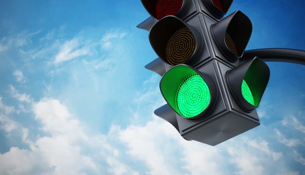 Green traffic light signaling go, blue sky background, urban transportation, road safety, traffic co.