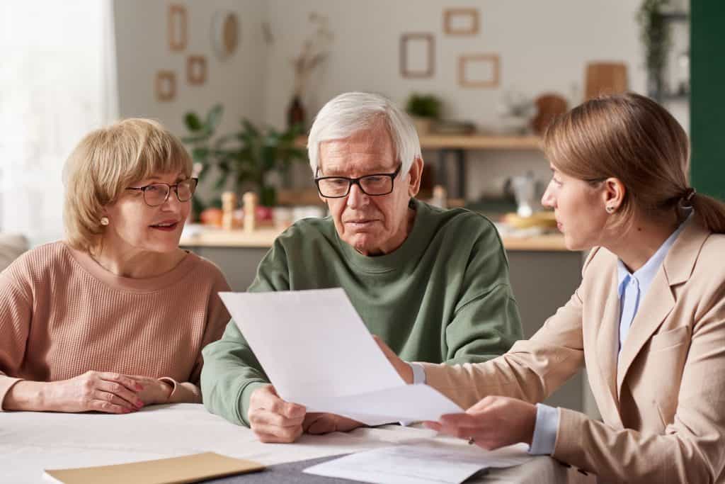 A senior man consulting with a lawyer and a woman in a cozy home setting, discussing legal matters related to estate planning.
