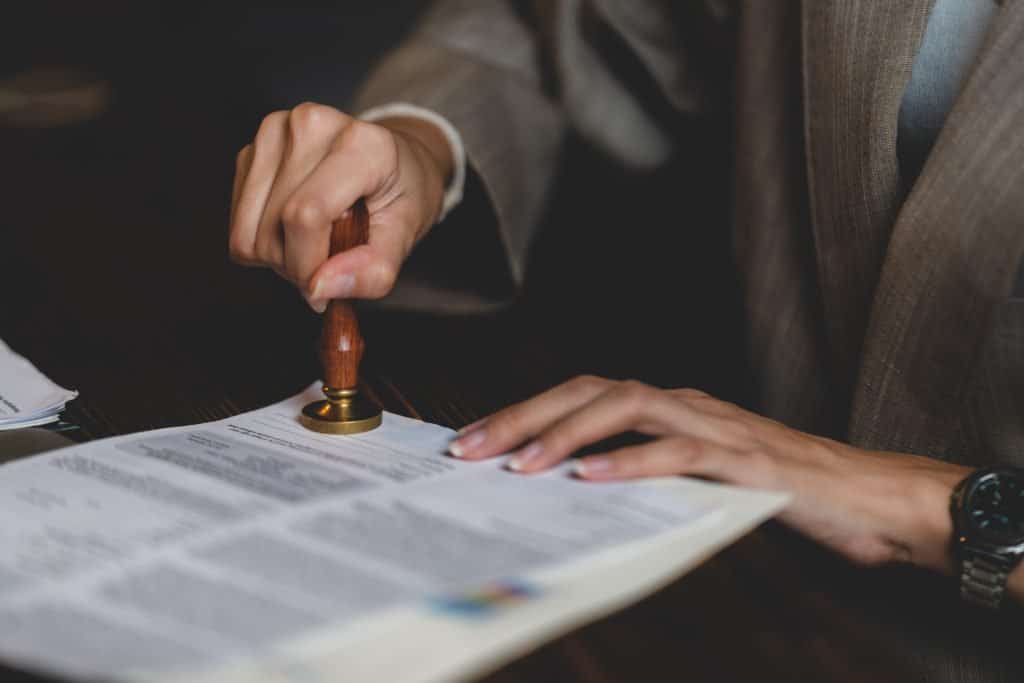 A person in a suit stamping a document, symbolizing legal action or official legal work, with a focus on law, legal services, and professional legal representation.