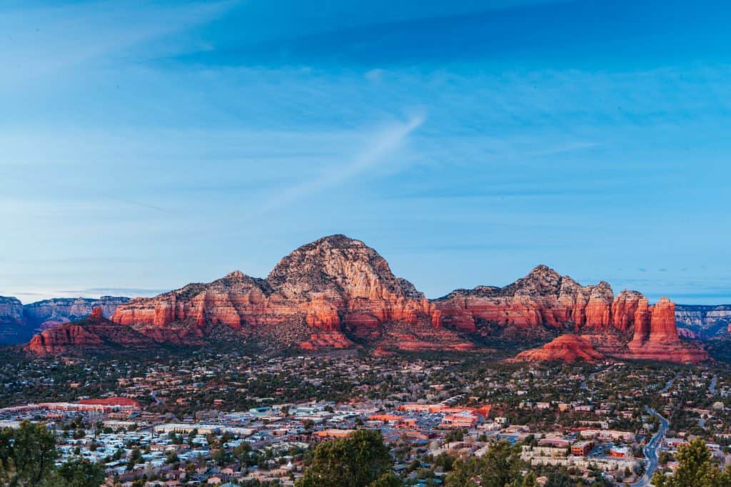 Arizona desert landscape with red rock formations and a city below, under a clear blue sky.