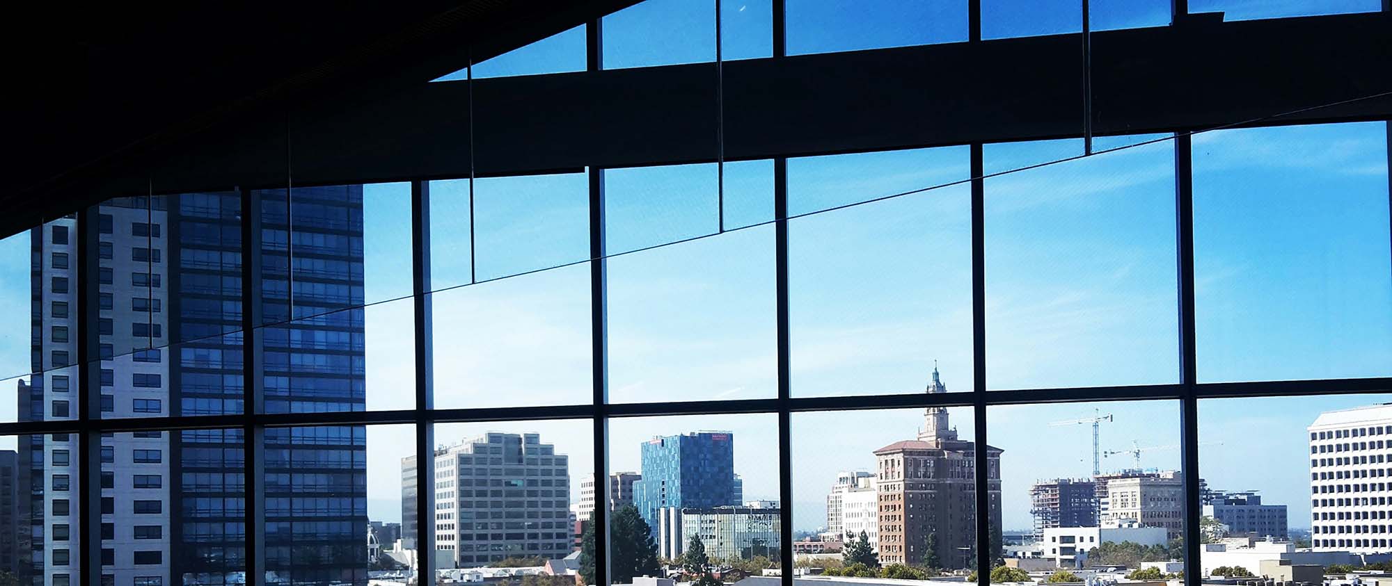 High-rise cityscape viewed through large glass windows in an office building.
