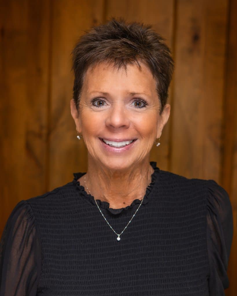 Professional woman smiling, legal expert, Dana Whiting Law office, wooden background.