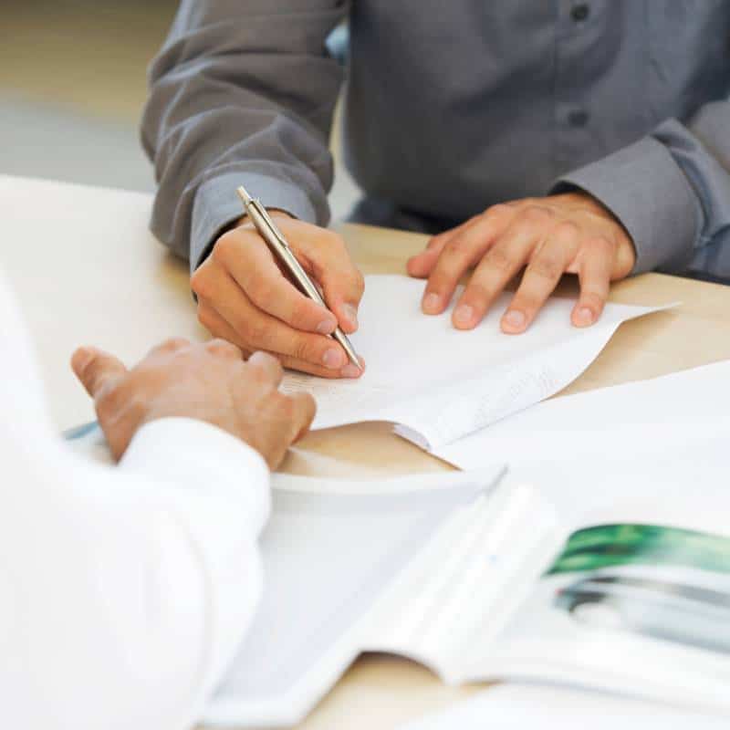 A person signing legal documents with a pen at a desk.