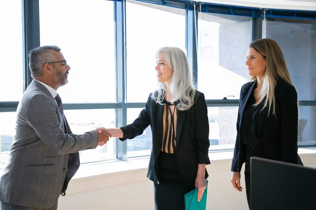 Business professionals shaking hands in a modern office setting.