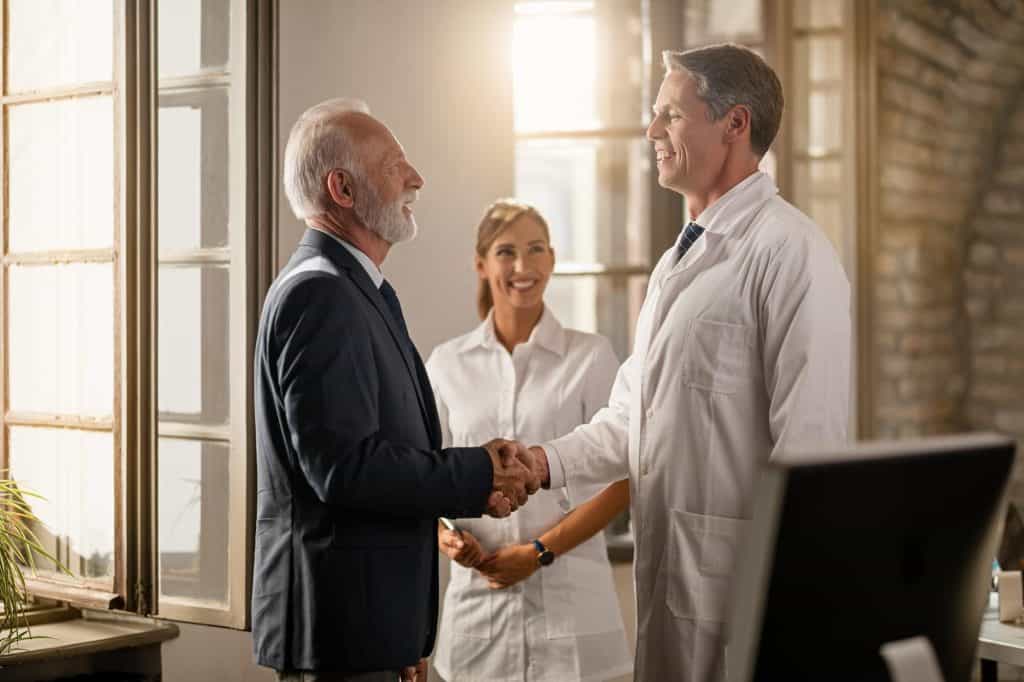 Experienced lawyer shaking hands with a client in a professional office setting.