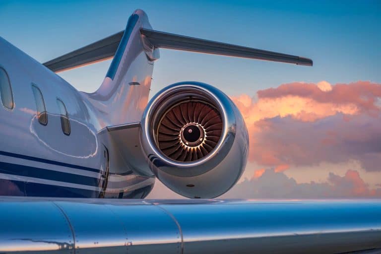 Private jet engine and tail at sunset, luxury travel aircraft.