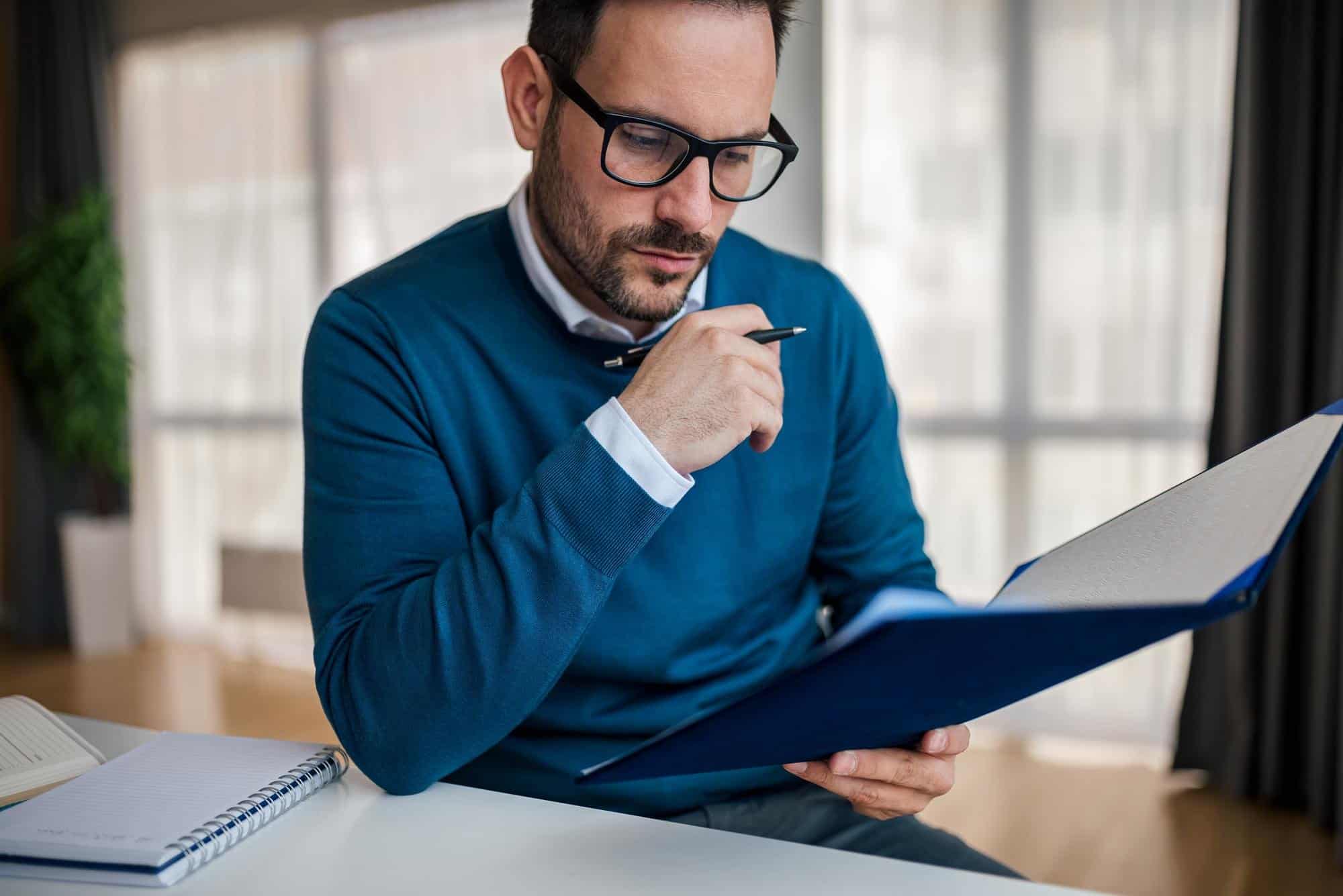 Business professional reviewing legal documents at desk in office.