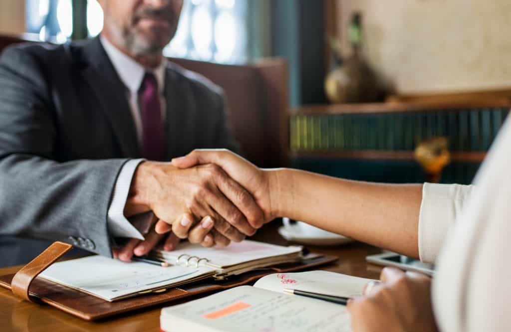 Lawyer shaking hands with client during legal consultation at law firm.