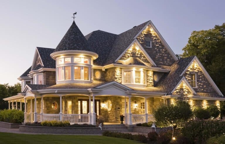 Elegant Victorian-style house illuminated at dusk, showcasing luxury real estate.